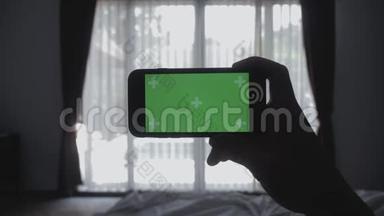 合上躺在床上的年轻人手里拿着智能手机绿色屏幕彩色键绿色屏幕分享真实的社交